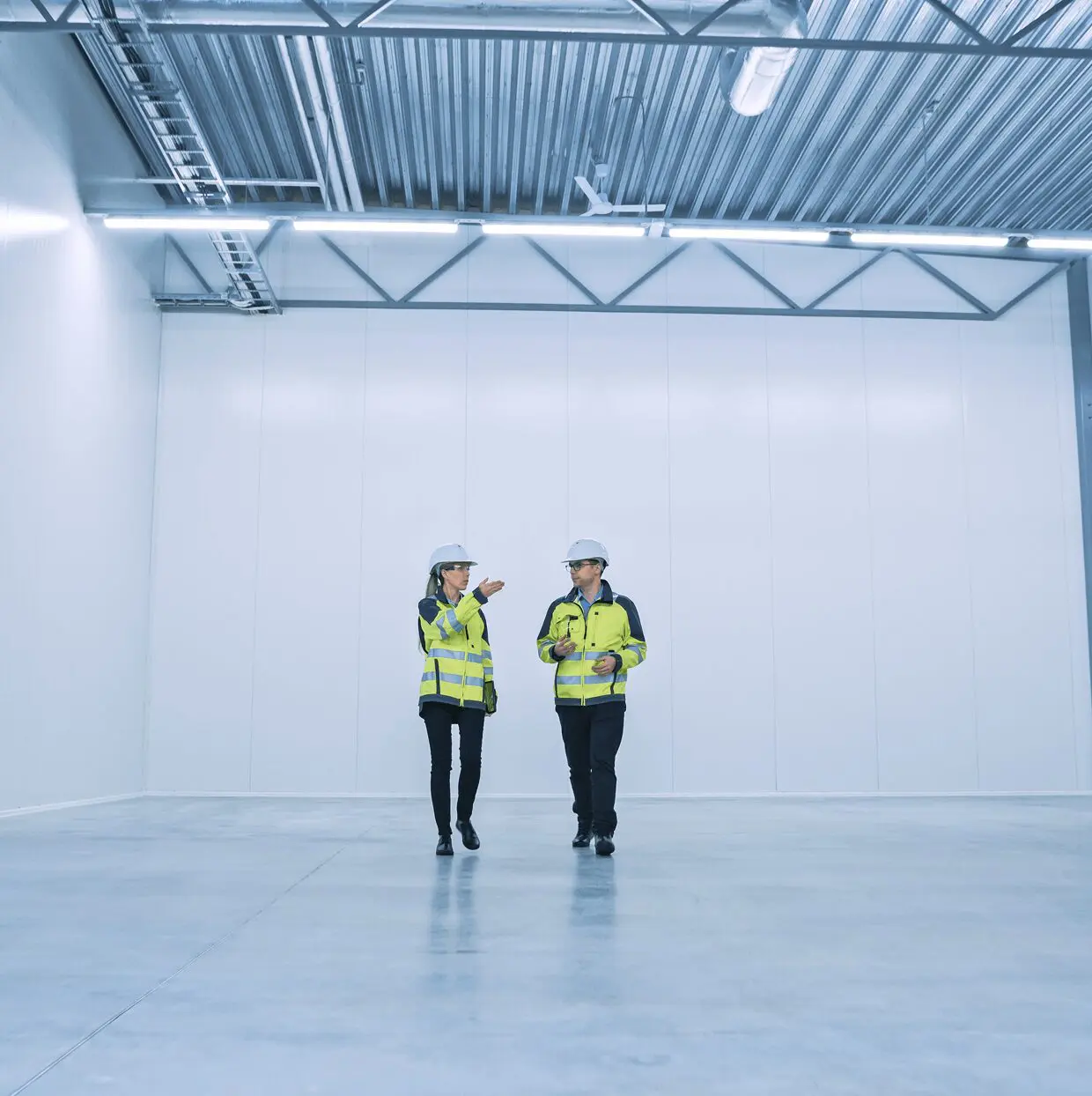 Two workers in an empty warehouse.